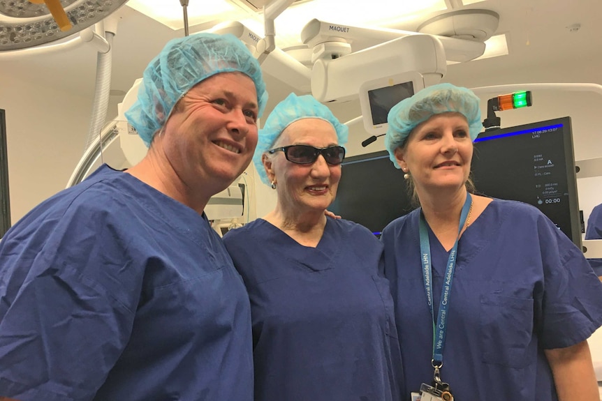 Three people in hospital hats and gowns.