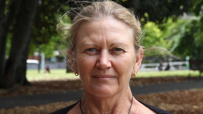 Portrait of woman with blonde hair standing in a park.