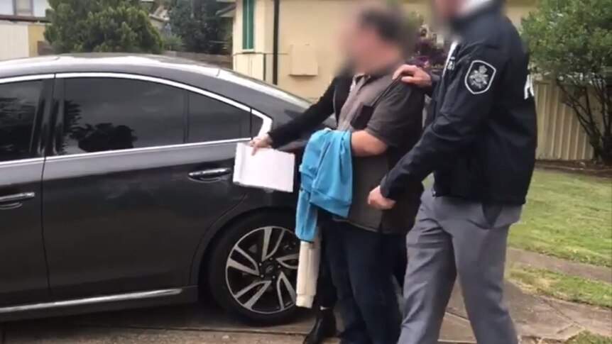 Police escort a man to a car