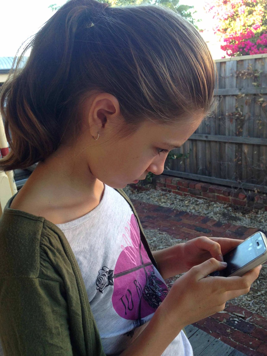 A young girl stares at a mobile phone screen.