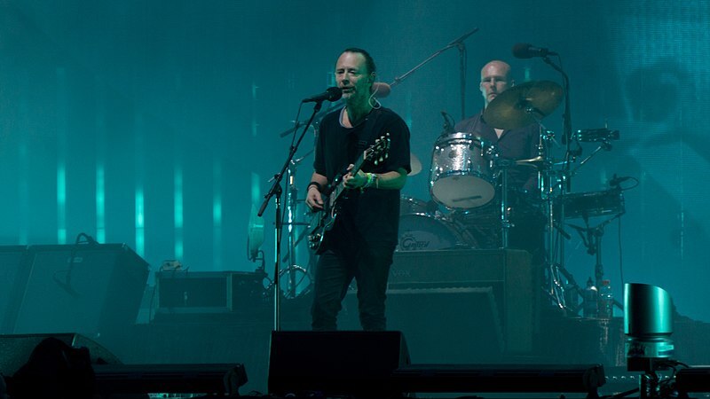 Radiohead playing on stag, Thom Yorke in foreground, drummer in background