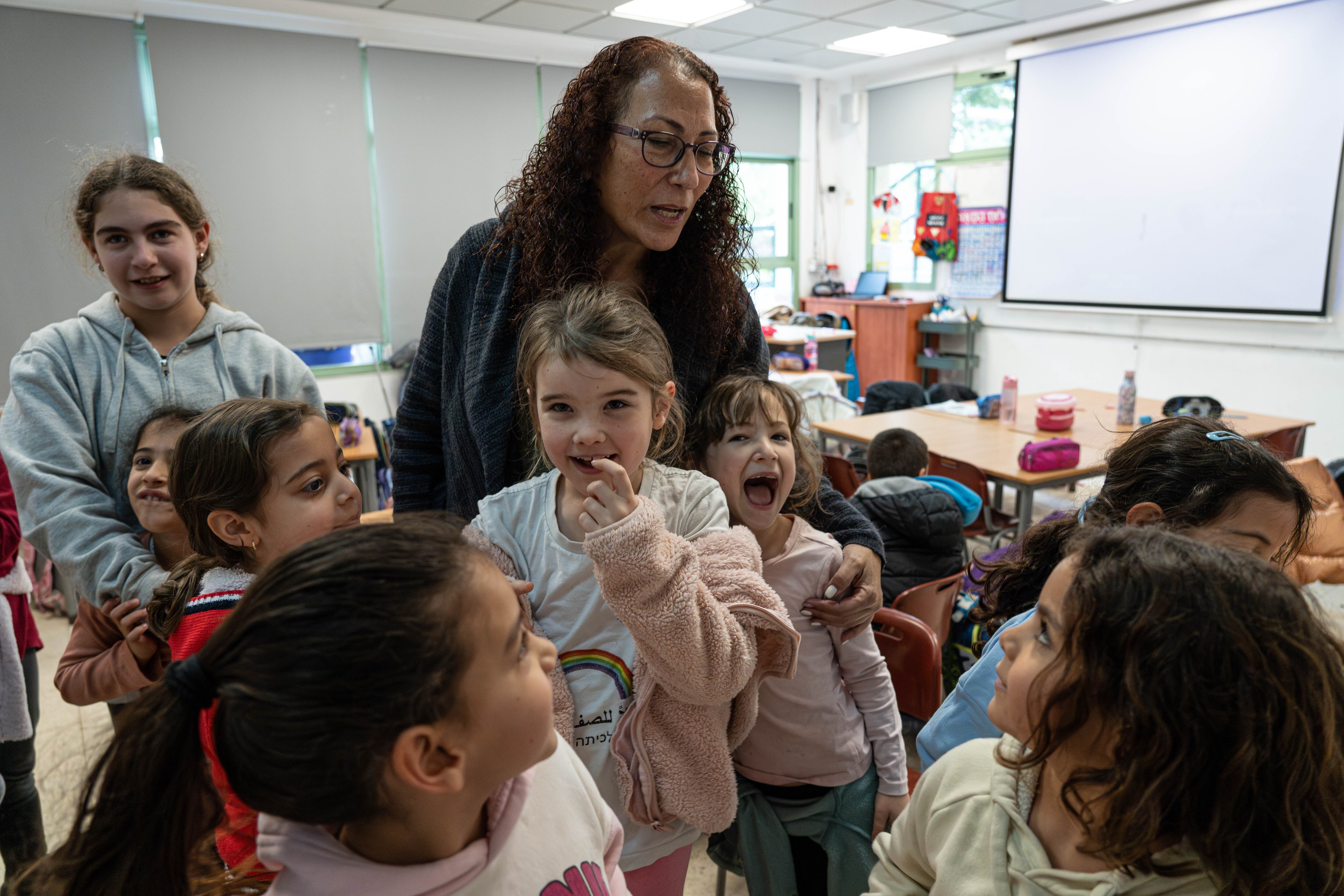 A teacher standing with a group of Palestinian and Jewish students in a classroom.