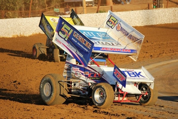 Two sprint cars racing on a dirt track