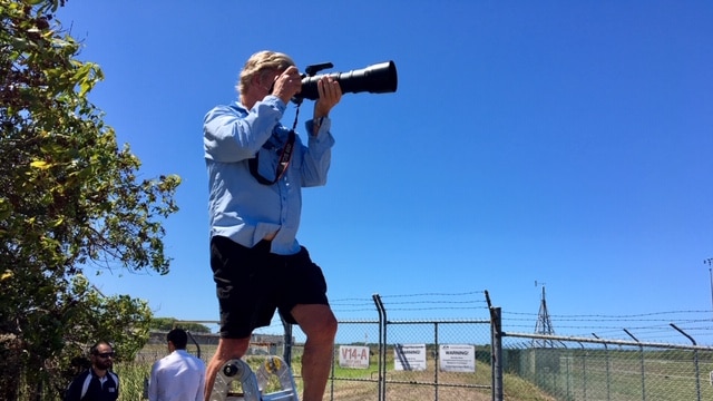 Plane spotter Steve Bottom stands on a step ladder with his camera.