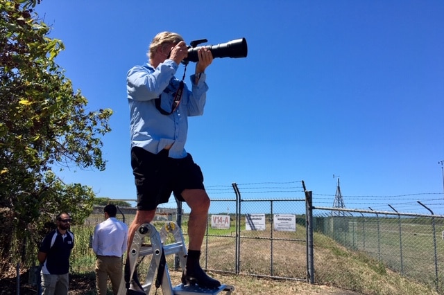 Plane spotter Steve Bottom stands on a step ladder with his camera.