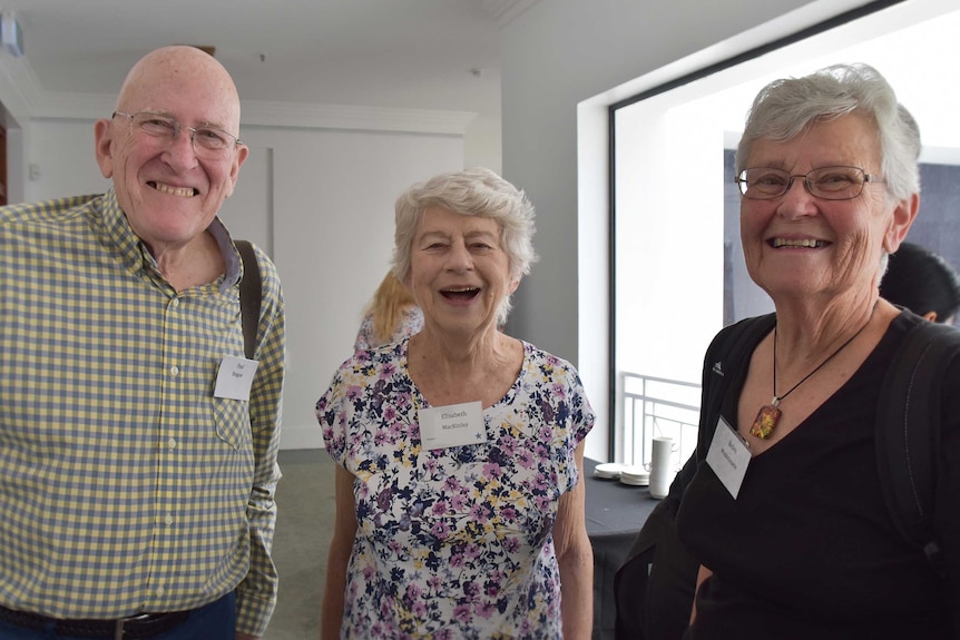 Three older people standing and smiling at the camera