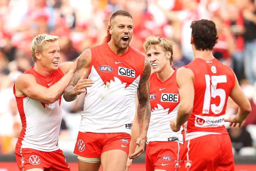 Lance Franklin is congratulated by a number of Swans teammates