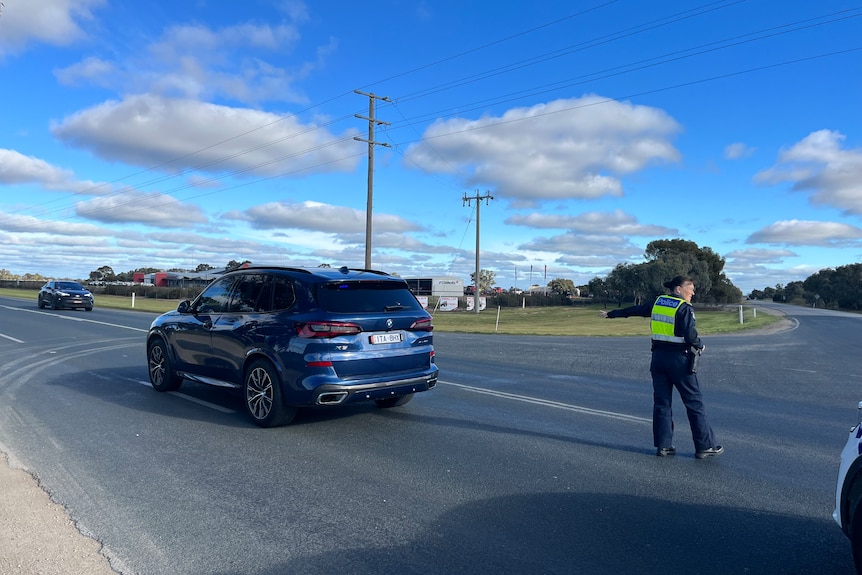 A police officer diverts traffic.