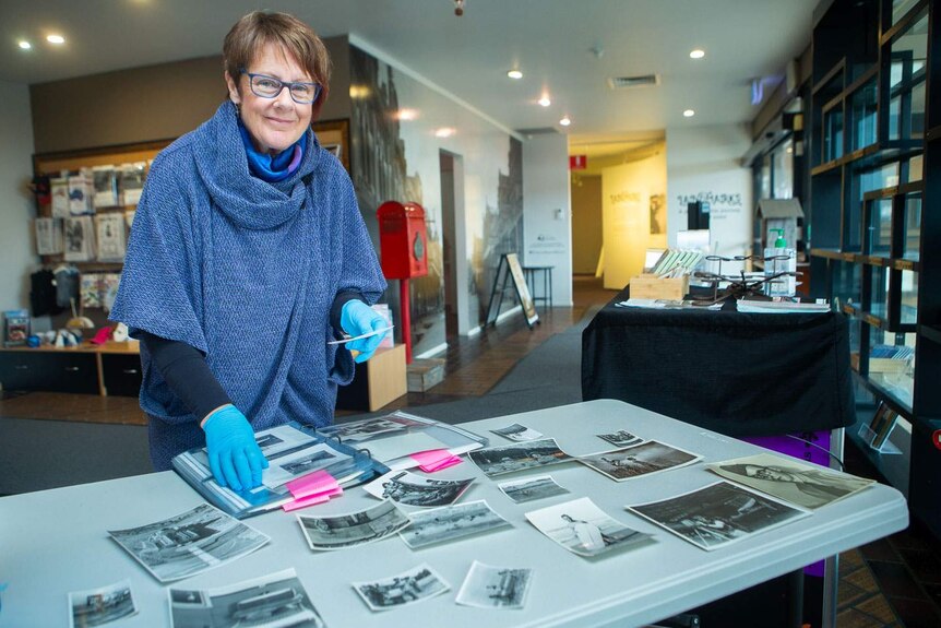 Smiling woman in archival gloves sorting black and white images on a table