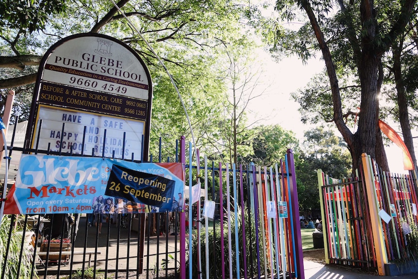 A sign saying Glebe Public School at a fence painted in different colours