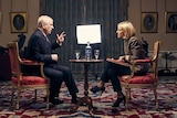 Prince Andrew sits on a chair opposite Emily Maitlis with a film crew in the background.