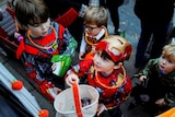 Children in Halloween costumes trick or treating at a doorway