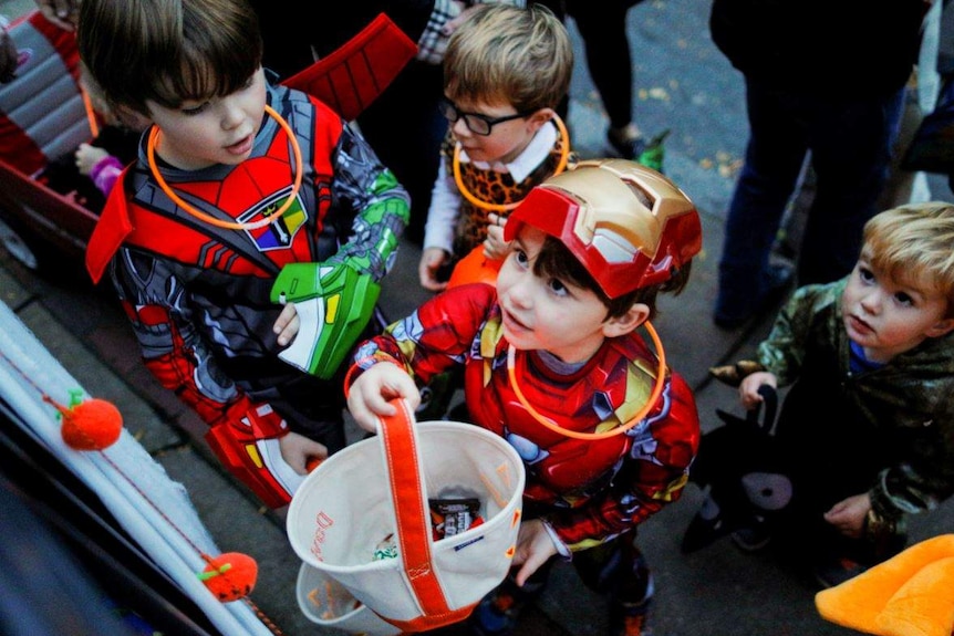 Children in Halloween costumes trick or treating at a doorway