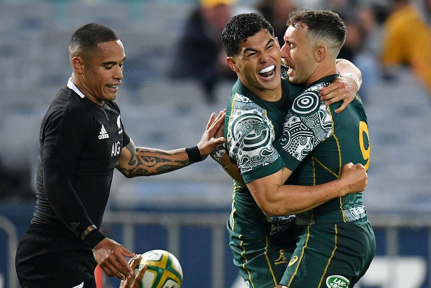 Two Wallabies players embrace as they celebrate scoring a try against the All Blacks.