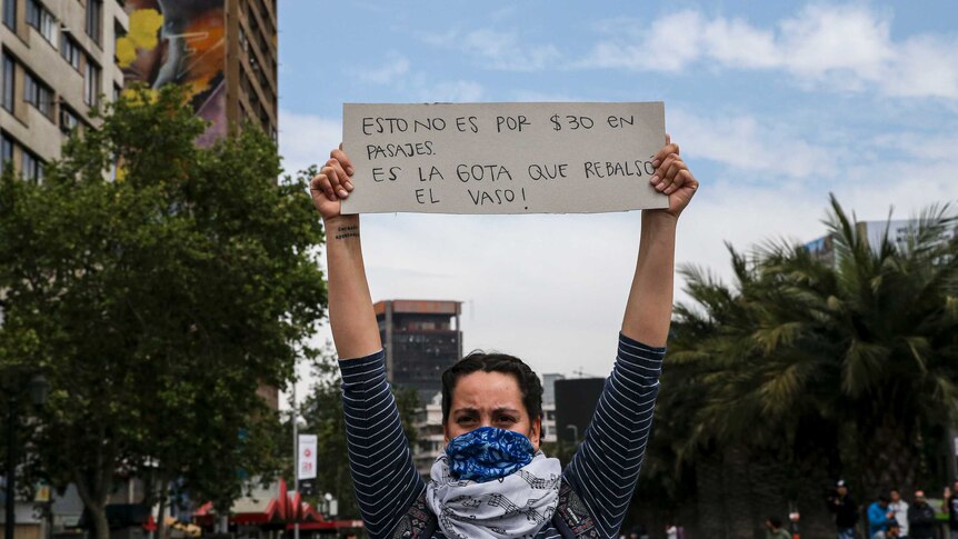 A demonstrator raises a sign that reads in Spanichs "This is not for 30 pesos in fare, it's the drop that overflows the glass"