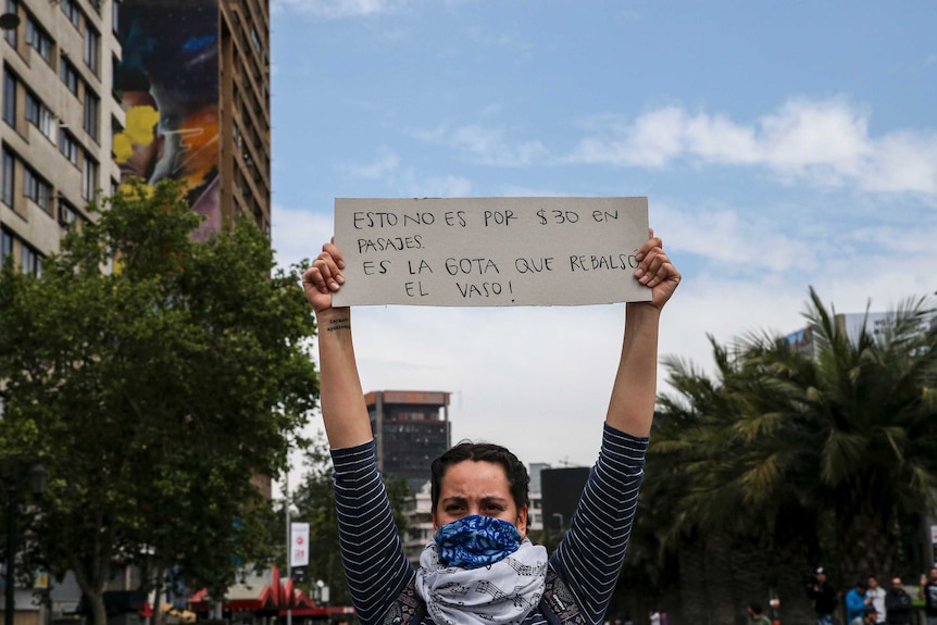 A demonstrator raises a sign that reads in Spanichs "This is not for 30 pesos in fare, it's the drop that overflows the glass"