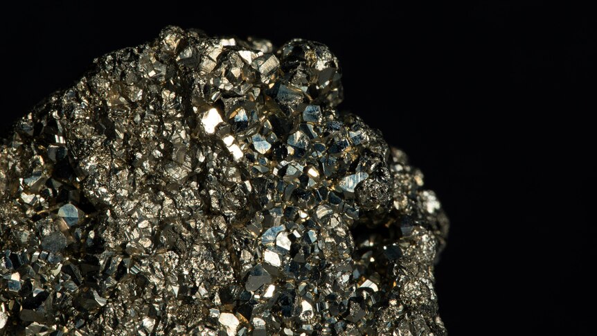 A closeup of a bumpy, faceted block of the mineral pyrite.