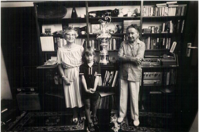 Black and white photo of an elderly couple and a boy with the America's Cup trophy in a loungeroom.
