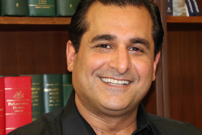 Yaz Mubarakai in front of a bookshelf in his office.