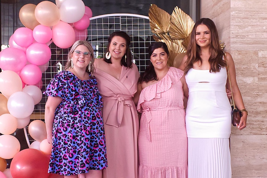 Endometriosis Queensland treasure Ash Webb and fellow members pose for photo near balloons.