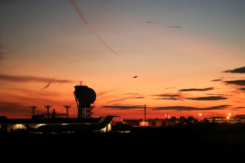 An airport silhouette in front of an orange sunset