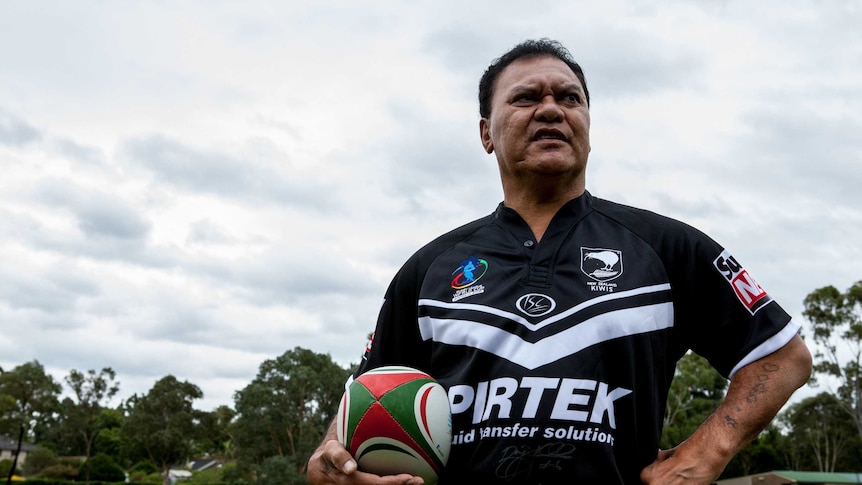 Olsen Filipaina standing on a rugby pitch holding a ball and wearing a NZ jersey