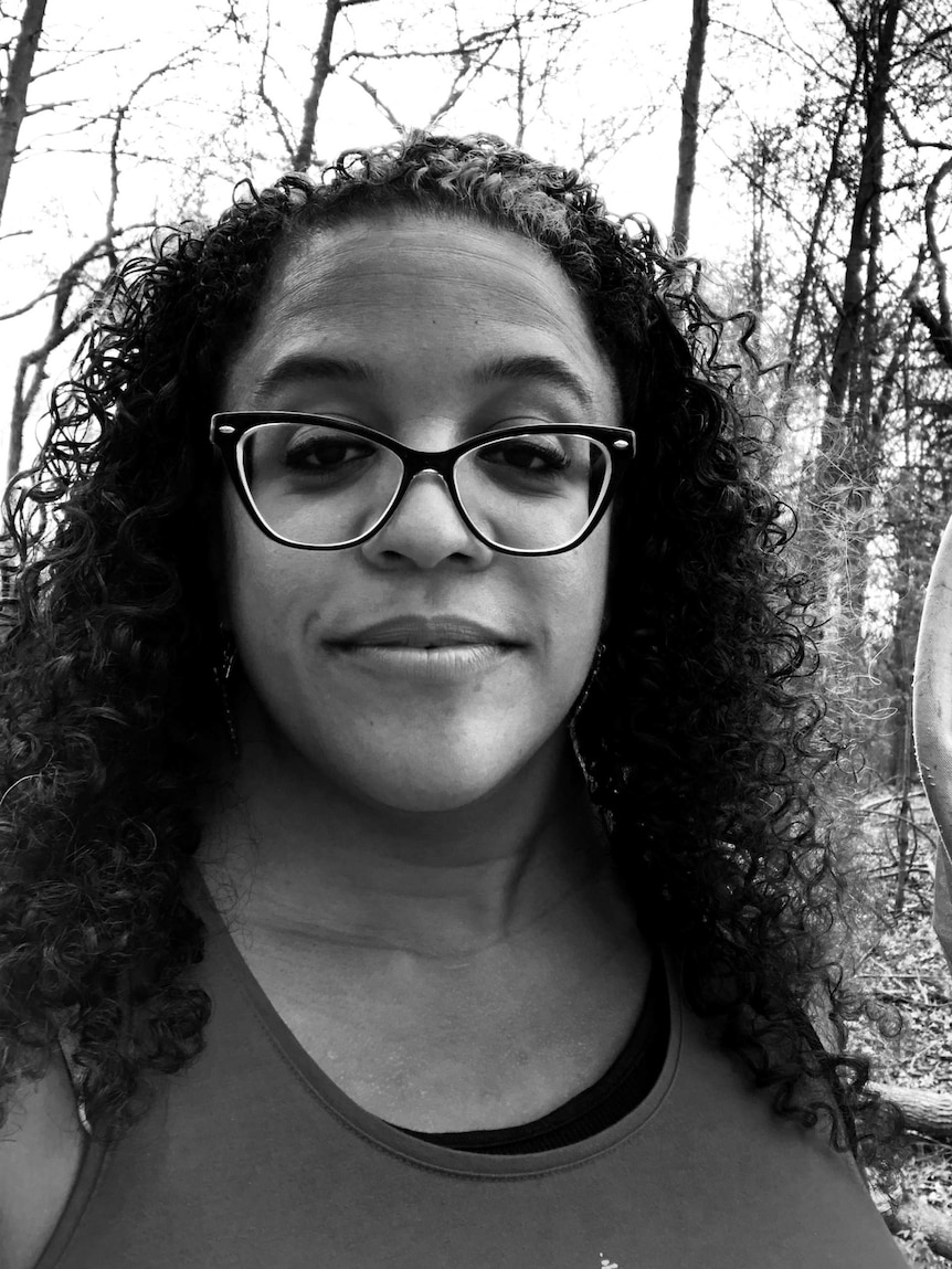 A black and white selfie of a woman wearing glasses and holding a net