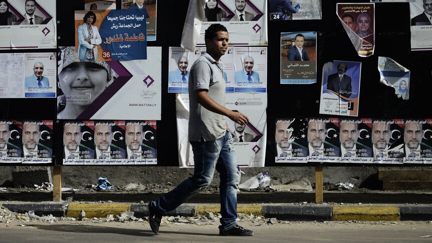 Man walks past election material as Libya prepares to vote