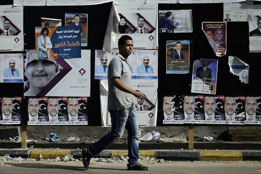 Man walks past election material as Libya prepares to vote