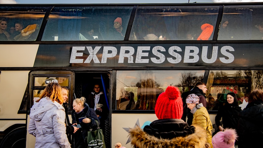 Families board a double decker bus with the words 'Express Bus' printed in large letters