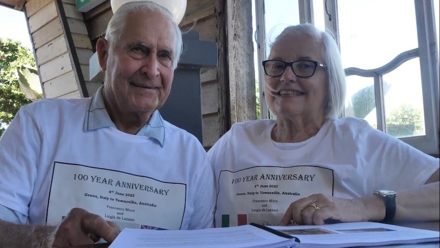 A woman and man, both wearing white t-shirts, smile for the camera.