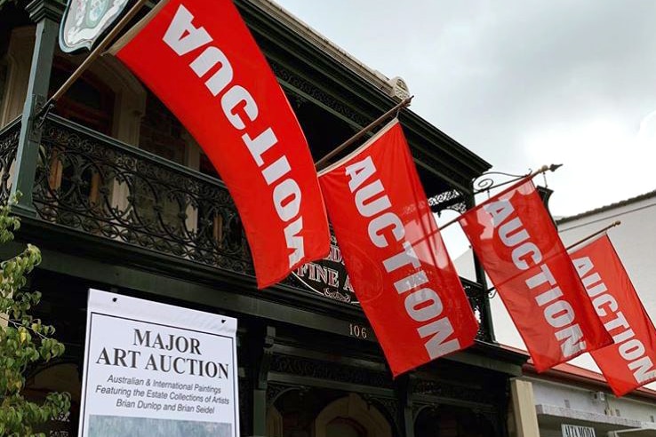 Image of a building with red auction flags waving outside