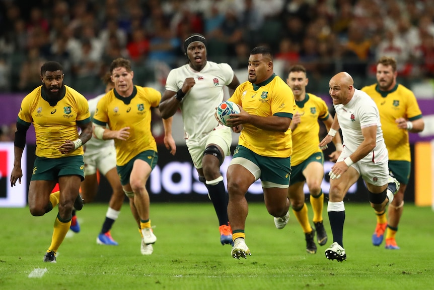 A Wallabies player runs downfield, turning sideways to see his support, as England defenders chase behind him.
