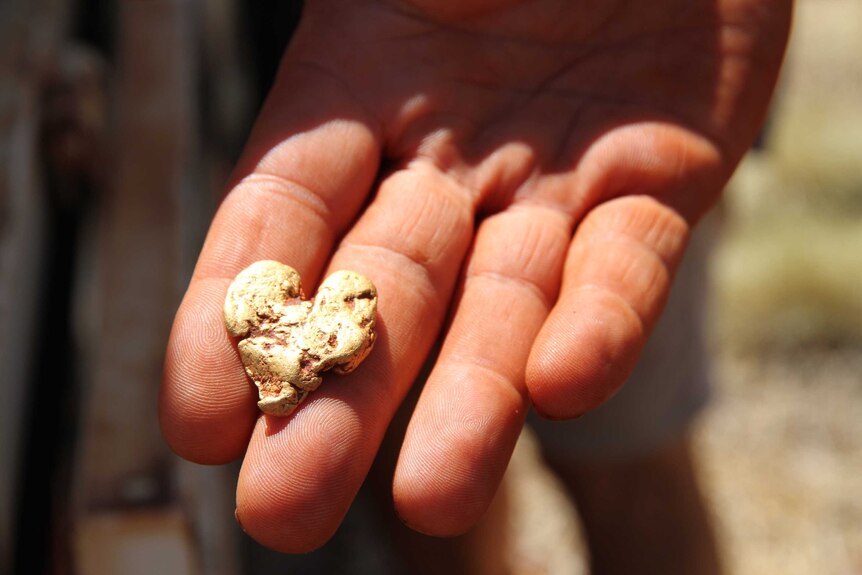 A heart shaped gold nugget its in a hand