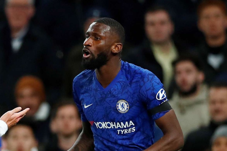 Antonio Rudiger holds his arms at his body.