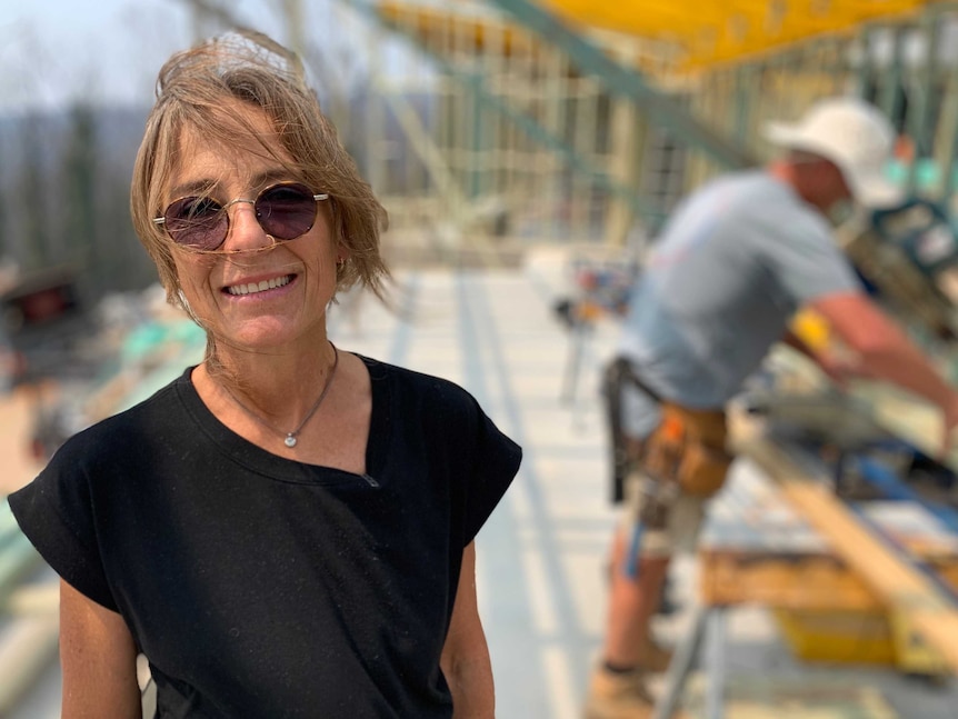 Michelle Carter wearing sunglasses stands in foreground, with a house construction site in background.