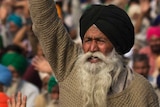 An elderly farmers shouts slogans as others listen to a speaker at a protest in India.