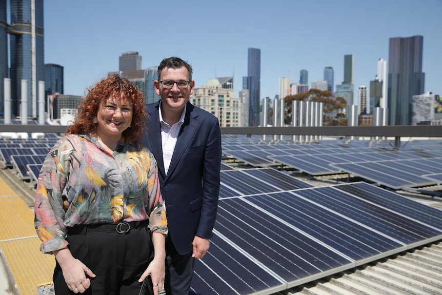 A man and a woman on a roof covered in solar panels