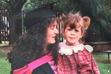 Jessica Amelia as a child is held by her mother, who is wearing a black graduation gown and cap.