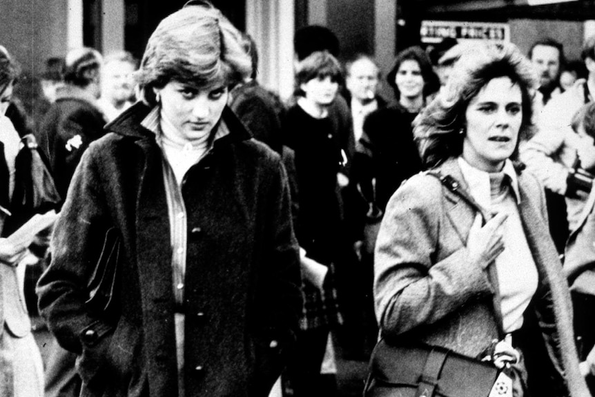 A black and white photo of Princess Diana dressed in a black coat and Camilla wearing a jacket 