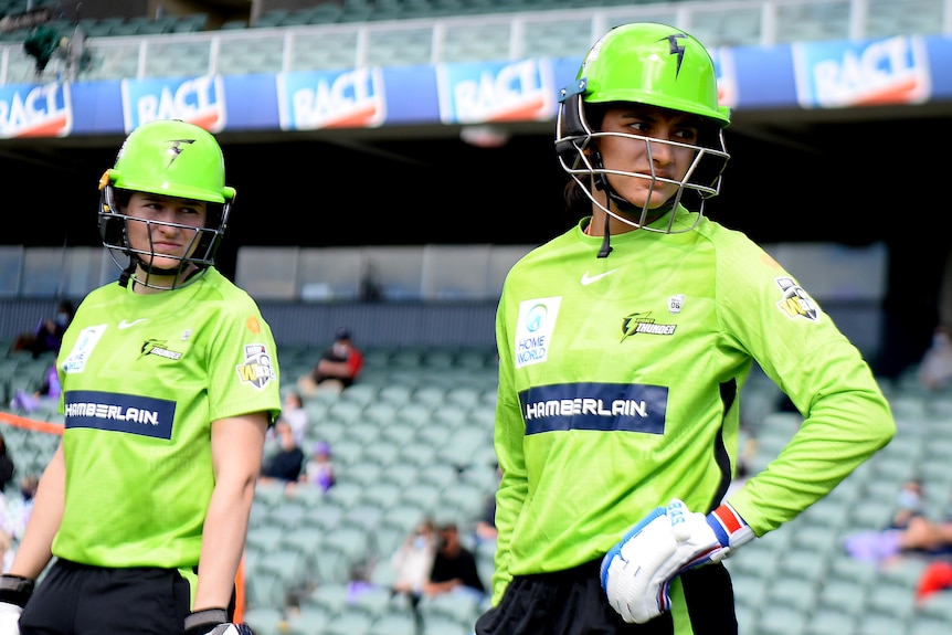 Smriti Mandhana and Tahlia Wilson stand waiting to walk onto the field.