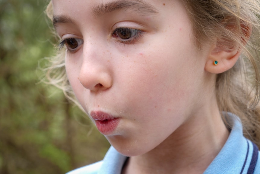 Close up of brown-eyed girl with pursed lips doing a bird call
