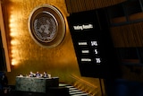 A screen reads in favour: 141, against: 5 and absentions 35 in the UN General Assembly chamber. 