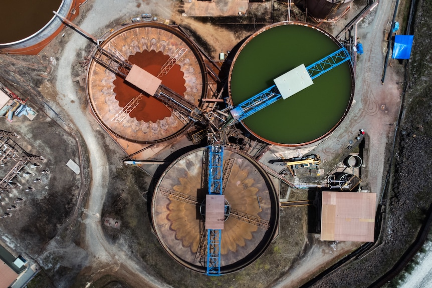 Una vista panorámica de enormes tambores industriales llenos de líquido verde y rojo. 