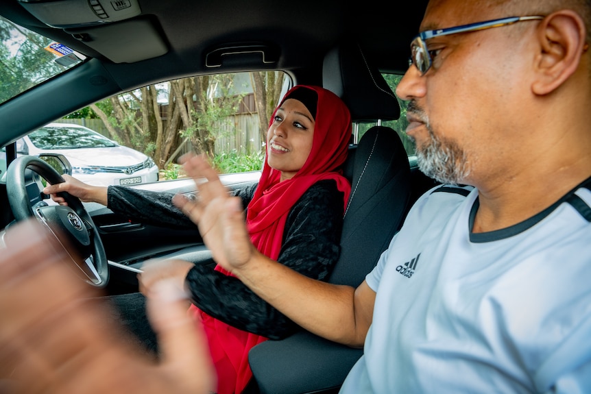 Huma Naz smiles as she drives, while Shahid sits in the passenger seat gesturing with his hands.