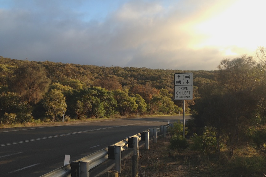 A roadside sign reads 'drive on left in Australia'.