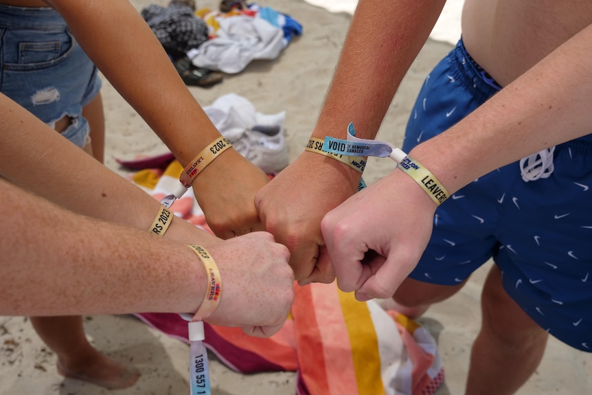 Five leavers put their hands in together to show off their wristbands for 2023 on the Busselton foreshore