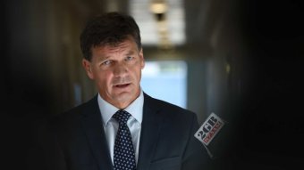 Angus Taylor in a suit being questioned by reporters