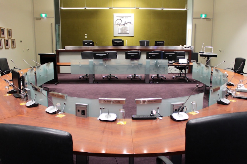 Chairs and desks in a semi circle as part of council chambers.