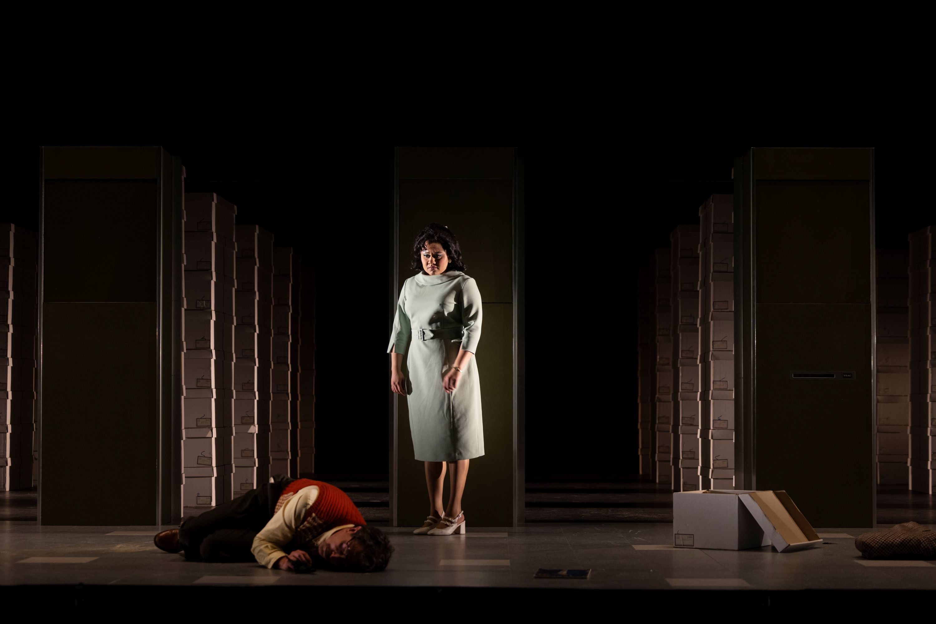On stage, Dan Spielman, 47, is lying on the floor, curled up. A concerned Manali Datar, 28, in a blue dress, looks down at him.